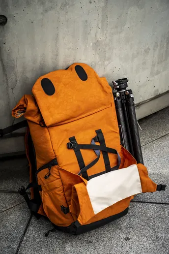 橙色背包和手提箱靠在人行道上的混凝土墙上