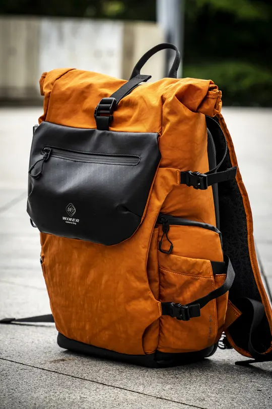 一只橙色的背包坐在人行道上 旁边是街道。