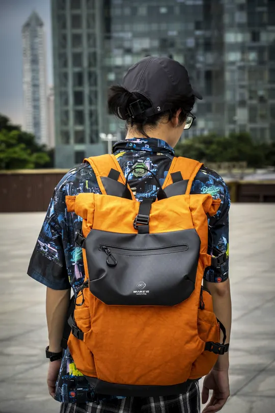 一个穿着橙色背包的男子抱着一个男孩在走。