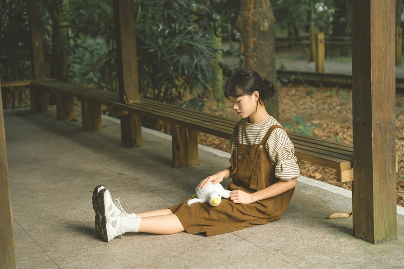 一位年轻女子坐在长凳的地面上