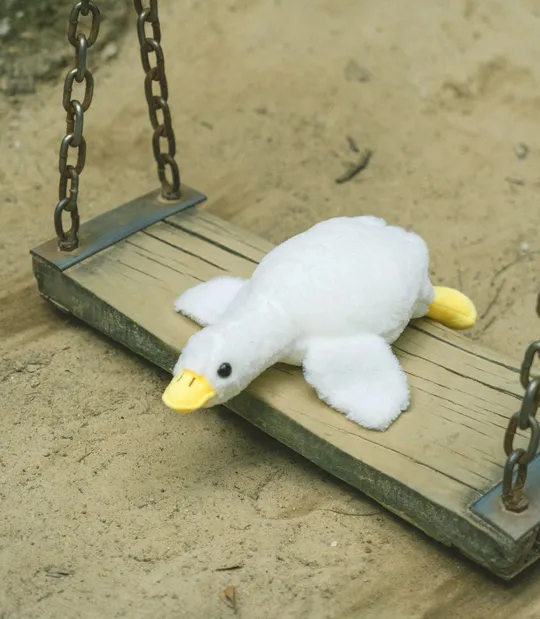 一只小白的鸭子玩具在木制秋千上