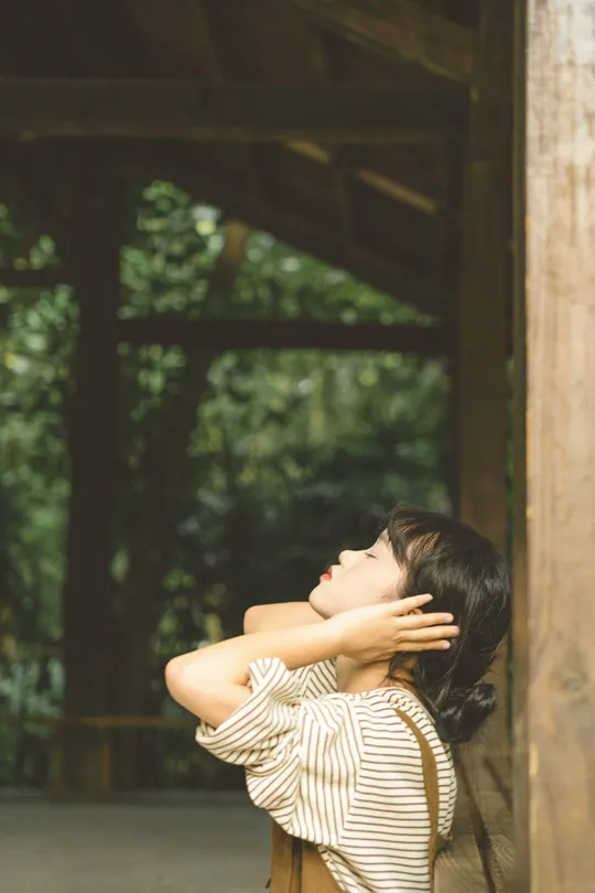一个年轻女子坐在木椅上 头埋在手中