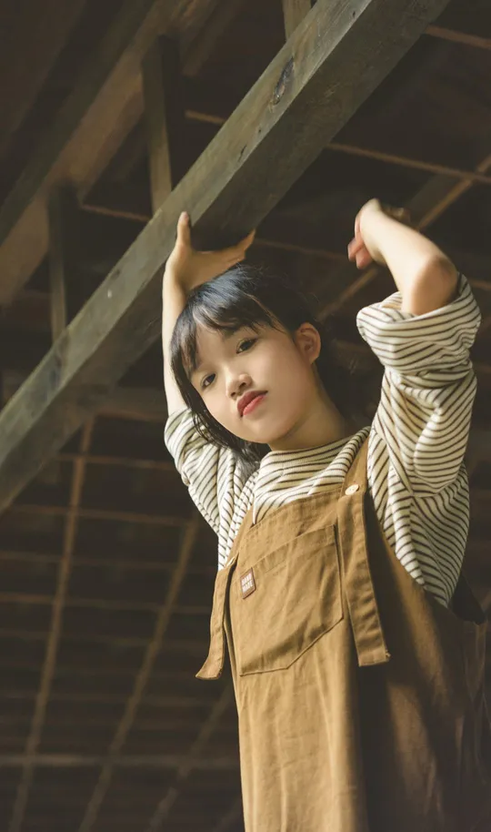 一个年轻女子站在一栋木质谷仓的阁楼里 双手伸展开来。