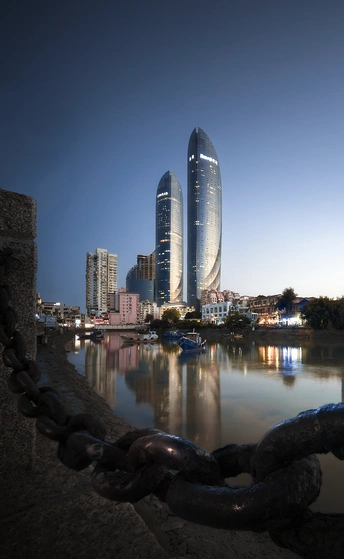 城市前方有一大片水域 背景是高耸的建筑物 前景是一条链条。