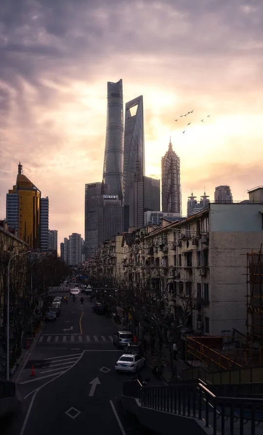 夕阳下的城市街道 有高楼和汽车在街道上。