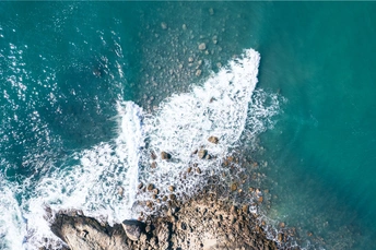 岩石海岸上的沙滩上 翡翠蓝色的海浪破碎的景象