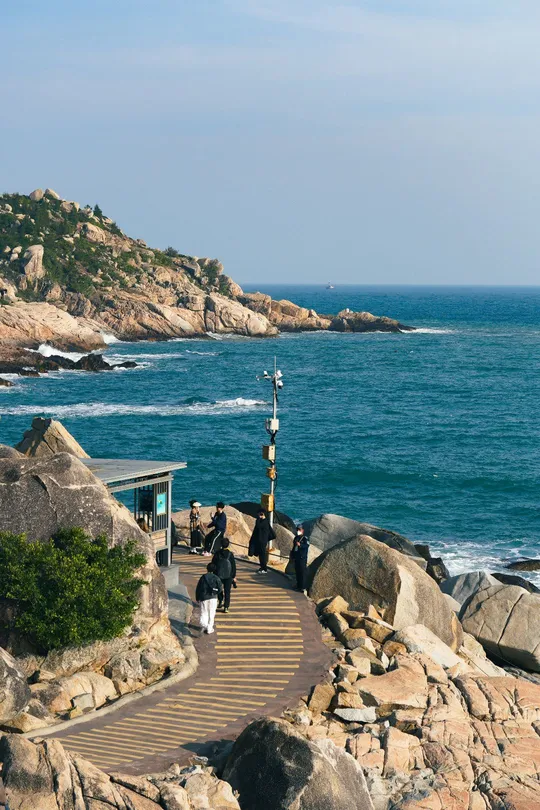 人们在靠近海洋的岩石小径上行走