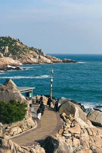 人们在靠近海洋的岩石小径上行走
