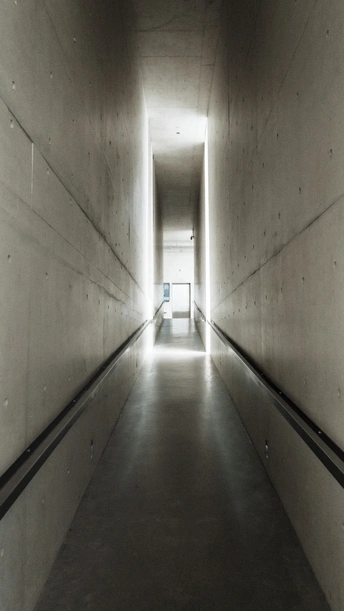 一条长长的走廊 墙壁由混凝土制成 通向隧道尽头的一盏灯。
