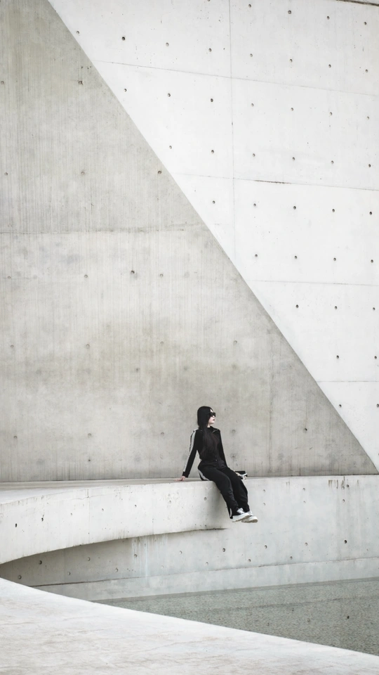 一个全黑的男人坐在建筑物的墙上