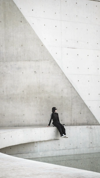 一个全黑的男人坐在建筑物的墙上