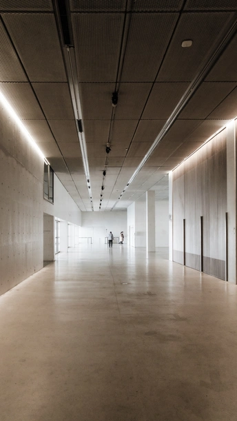 一个宽敞的房间 墙壁和地板都是白色的 天花板上装有灯。