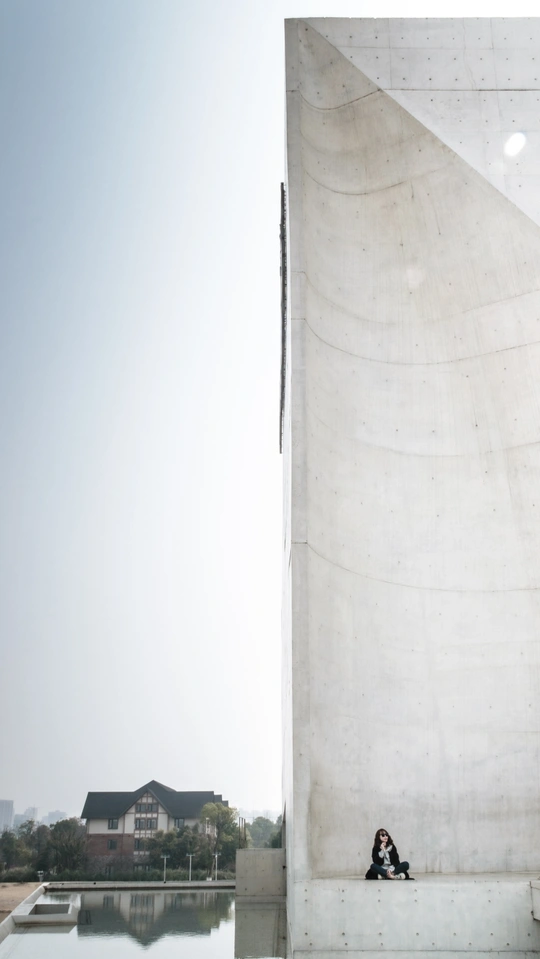 一位妇女坐在水池前面的纪念碑上。