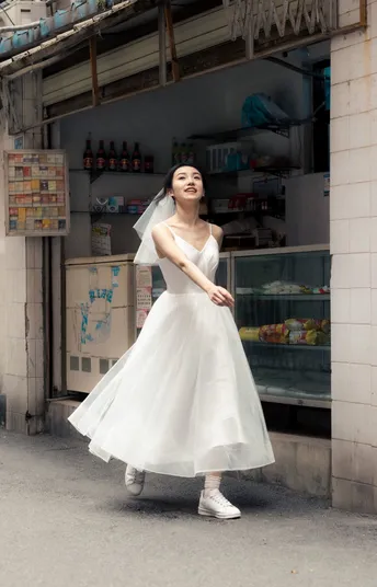 一位穿着白色婚纱的年轻女子走在街上