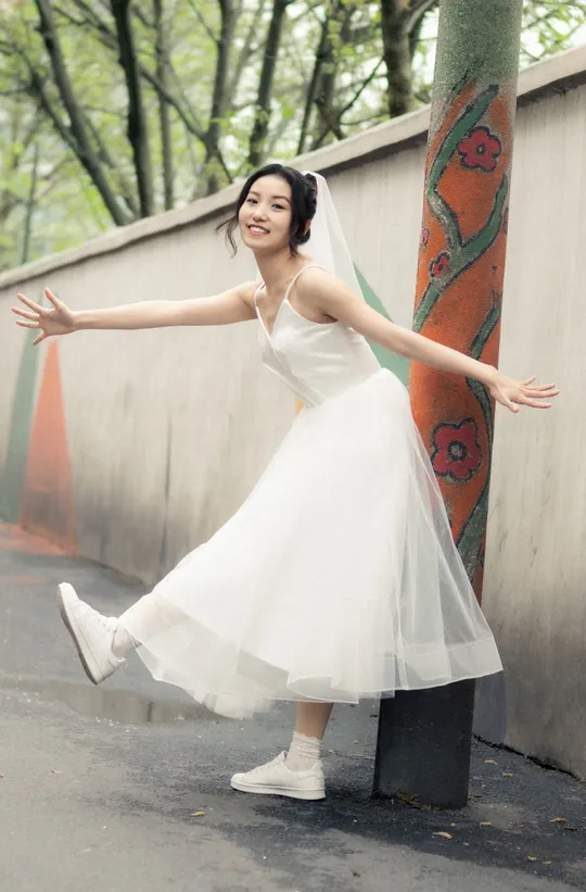 一位穿着白色连衣裙的女士正在街上跳舞。