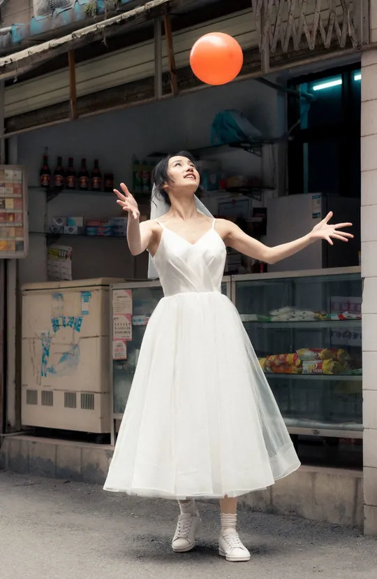 一位穿着白色连衣裙的年轻女子拿着一个橙色球