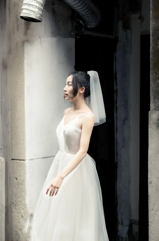 一个穿着白色婚纱的女人站在一座废弃的建筑中
