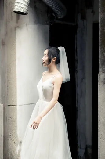 一个穿着白色婚纱的女人站在一座废弃的建筑中