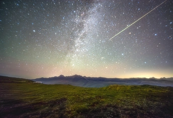 夜空中的星星和山脉上的一颗流星