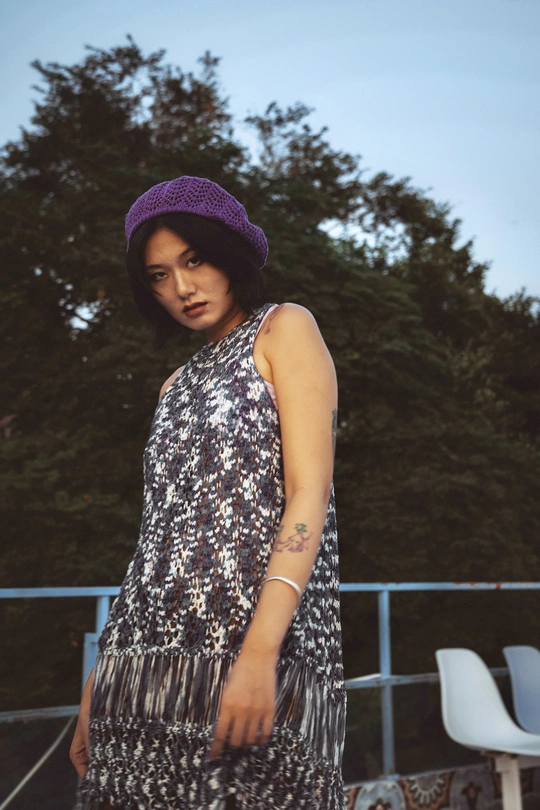 一位穿着紫色连衣裙和紫色帽子 站在滑板上的年轻女子