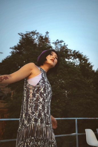 一位年轻女子穿着裙子 伸出手臂去接飞盘。