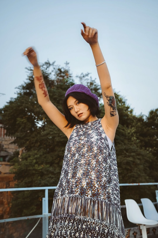 一位穿着紫色连衣裙和紫色帽子的年轻女子张开双臂 双手举过头顶。