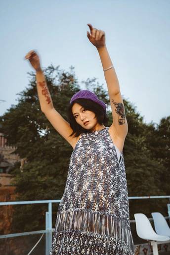 一位穿着紫色连衣裙和紫色帽子的年轻女子张开双臂 双手举过头顶。