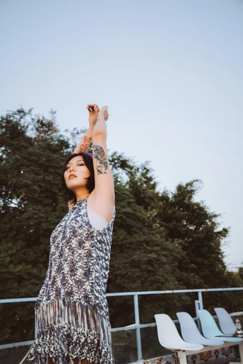 一个穿着连衣裙的年轻女子举起手向天空 一个飞盘在她的头顶上方伸展。