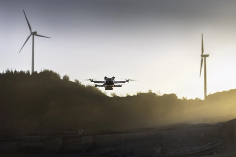 夕阳下飞过风力发电场的小飞机与风车背景