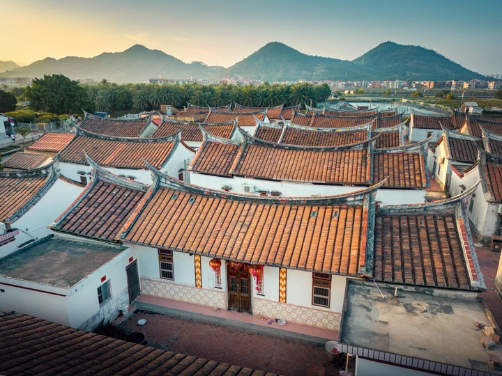 夕阳下中国古城的瓦房屋顶的空中视角 背景是山脉。