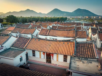 夕阳下中国古城的瓦房屋顶的空中视角 背景是山脉。