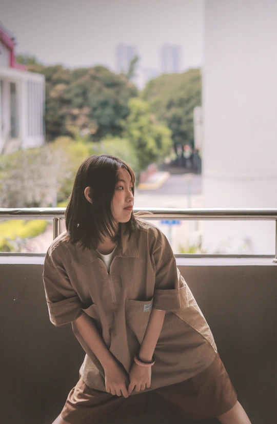 一位年轻女子坐在阳台上 在窗户前摆姿势