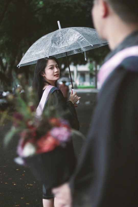 一位年轻女子手持透明雨伞在雨中走下街道