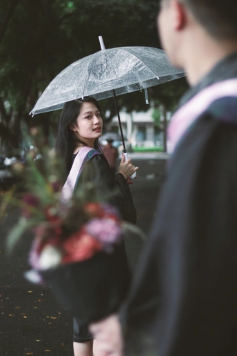 一位年轻女子手持透明雨伞在雨中走下街道