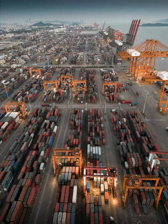 一艘大型货船在有多个起重机在水中的港口停靠。