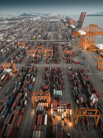 一艘大型货船在有多个起重机在水中的港口停靠。