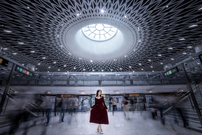 一位穿着红色连衣裙的女士站在一个有穹顶的大楼里