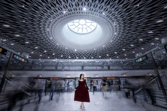 一位穿着红色连衣裙的女士站在一个有穹顶的大楼里