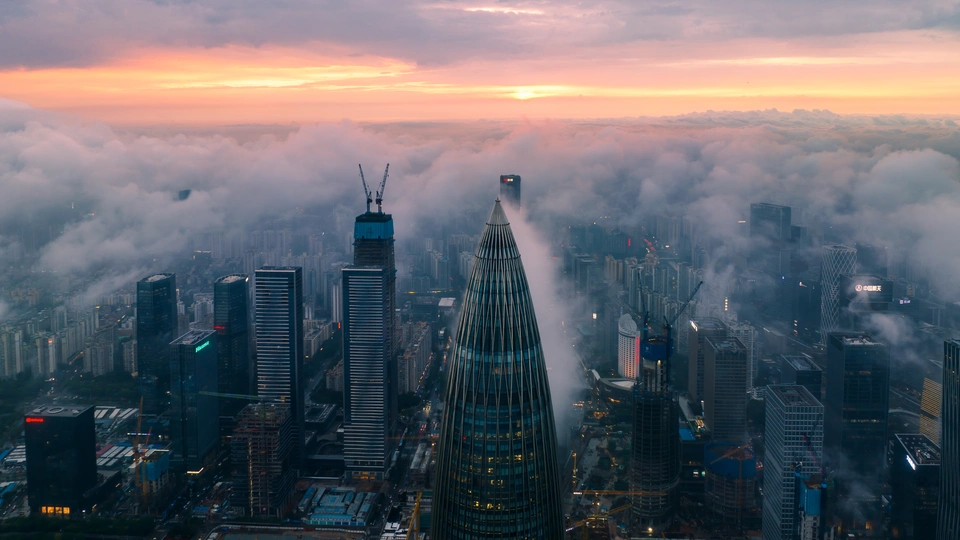 日落时天空线的航拍视角 包括雾气和云层 以及高楼的顶部。