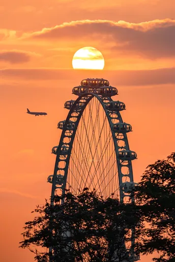 夕阳下的大型法拉利轮 一架飞机在天空中飞行。