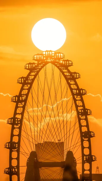 夕阳下 一个巨大的铁轮在橙色天空中。