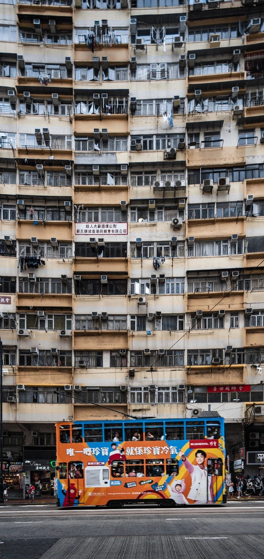 公交车在一条街道上驶过 前面有一栋高楼。