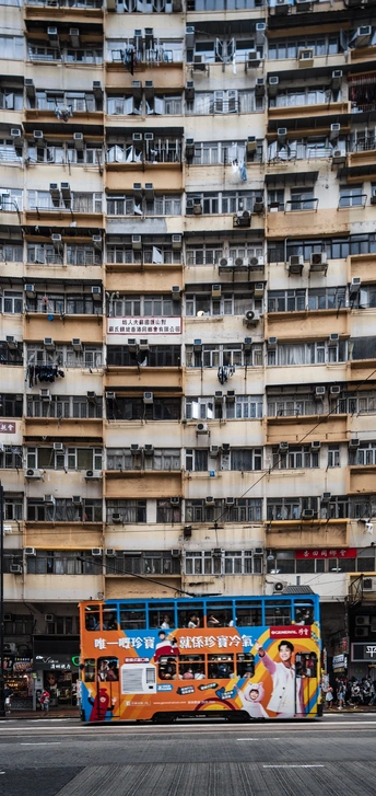 公交车在一条街道上驶过 前面有一栋高楼。