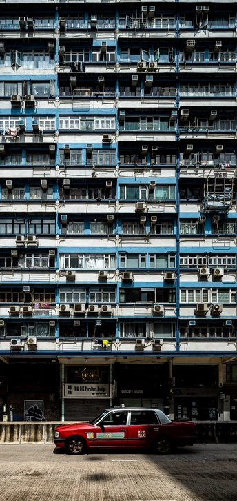 一辆红色的车停在了一栋高楼大厦的前面。