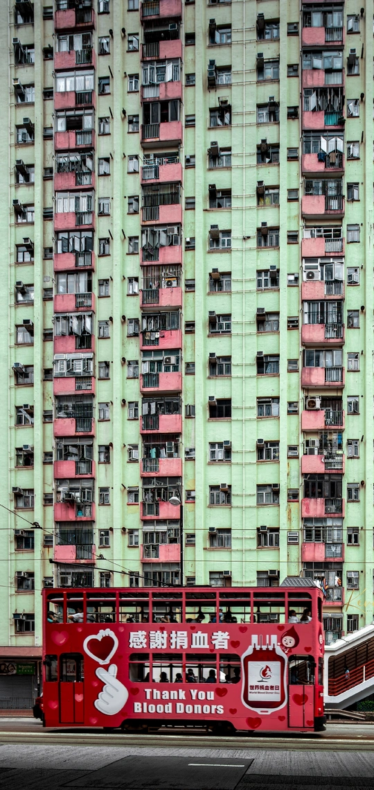 红色双层公交车驶过城市中的高楼大厦