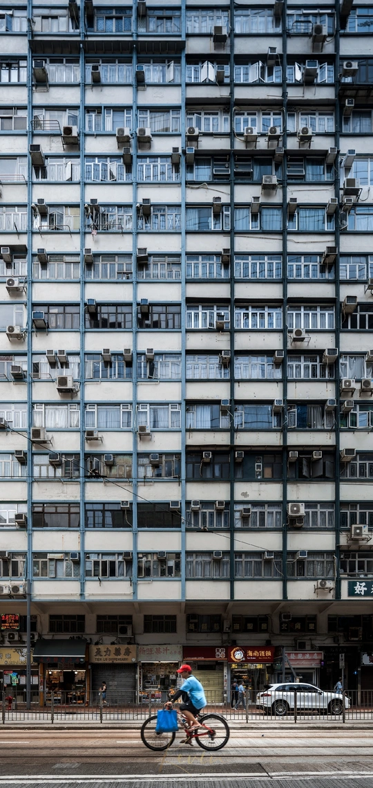 一个人骑自行车在高层公寓楼前街道上