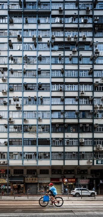 一个人骑自行车在高层公寓楼前街道上
