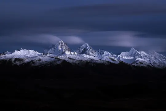 夜晚被满月照亮的一座白雪皑皑的山脉
