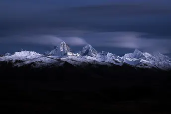 夜晚被满月照亮的一座白雪皑皑的山脉