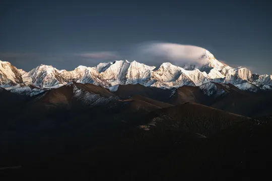 雪覆盖的山脉 阳光和云彩照耀